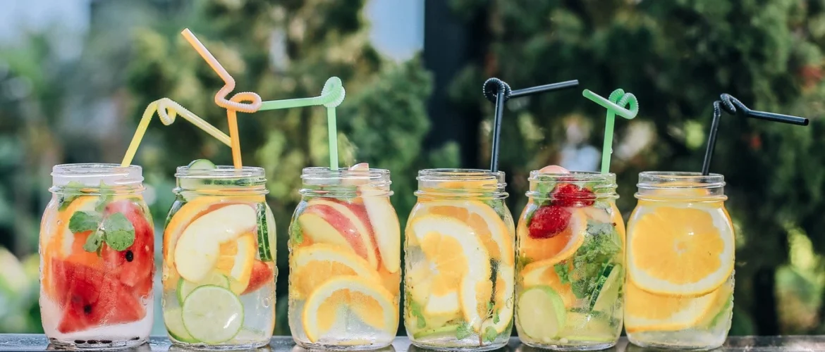 Bebidas hidratantes naturales con trozos de frutas sobre una mesa.